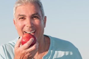 a man eats an apple using the strength of his dental bonding results